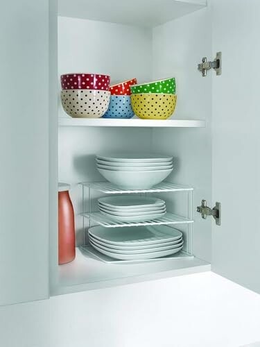 Bol multicolore et assiettes blanches dans un placard.